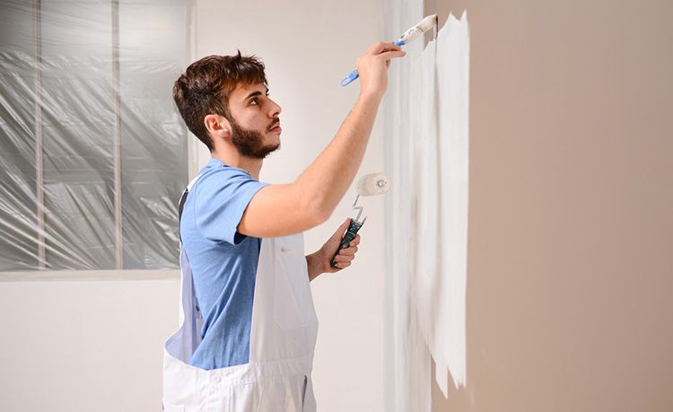 Junger Maler-Azubi bereitet eine Wand zum Streichen vor.