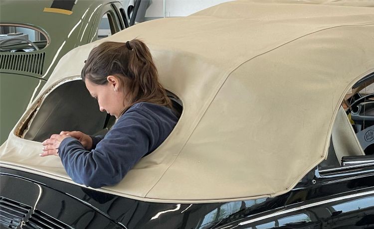 Eine Autosattlerin verkleidet den Außenbereich eines VW Beetles