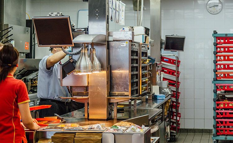 Leute stehen in einer Küche in einem Fastfood-Restaurant.