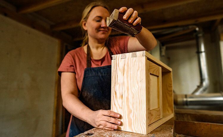 Junge Zimmerin bearbeitet ein Holzbauteil.